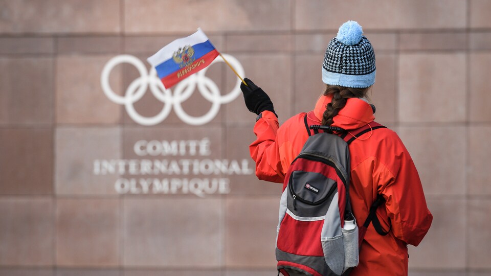 Une femme agite un drapeau de la Russie devant le quartier général du Comité international olympique, à Lausanne, en Suisse.