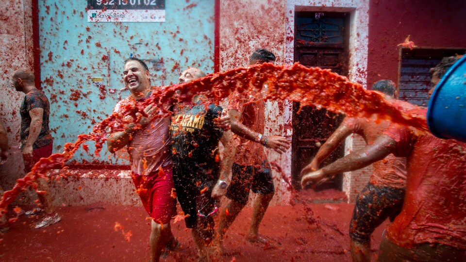 Des festivaliers s'aspergent de pulpe de tomates aux festival Tomatina du village de Bunol, en Espagne.