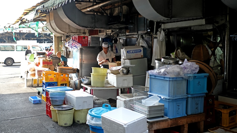 Un commerçant travaille derrière des boîtes au marché de poisson de Tsukiji.