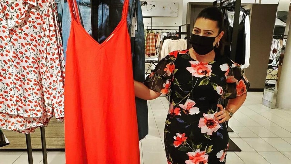 Une femme pose dans un magasin de vêtement.