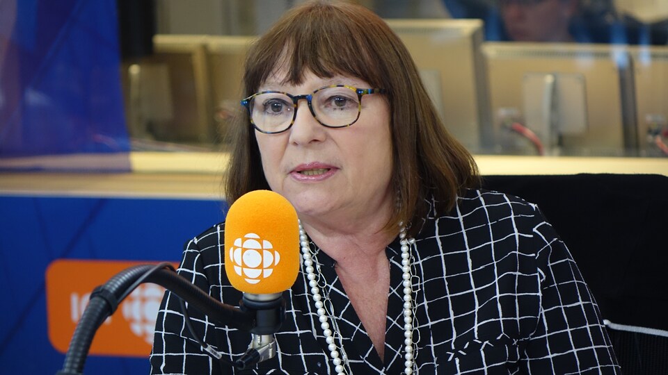 Monique Simard derrière un micro dans un studio radio de Radio-Canada.