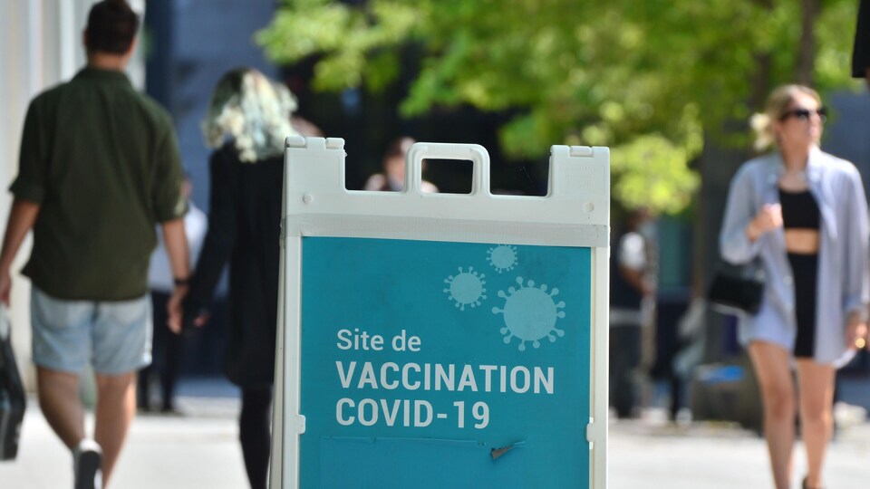 Des passants près d'un centre de vaccination contre la COVID-19 à Montréal.