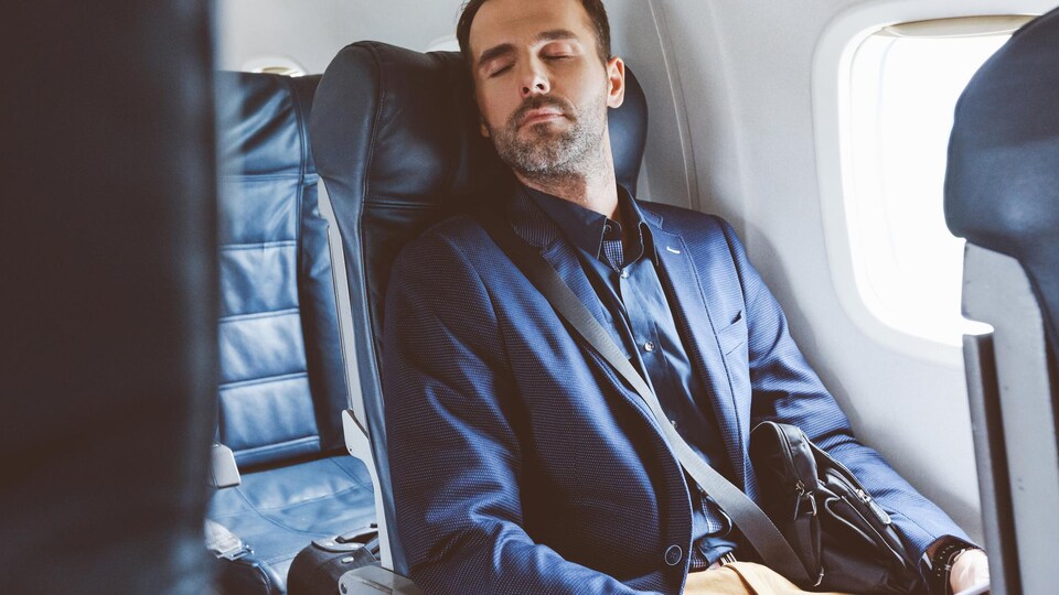 Un homme d'affaires dort dans un avion.