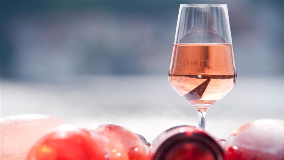 Un verre de vin rosé déposé sur une table.