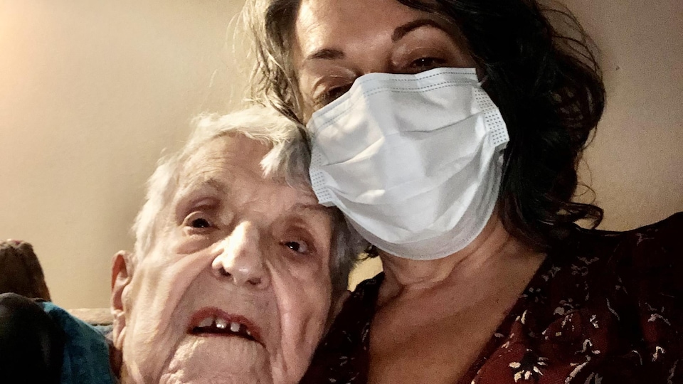 Une femme qui porte un masque se colle à sa mère, qui est atteint de COVID-19