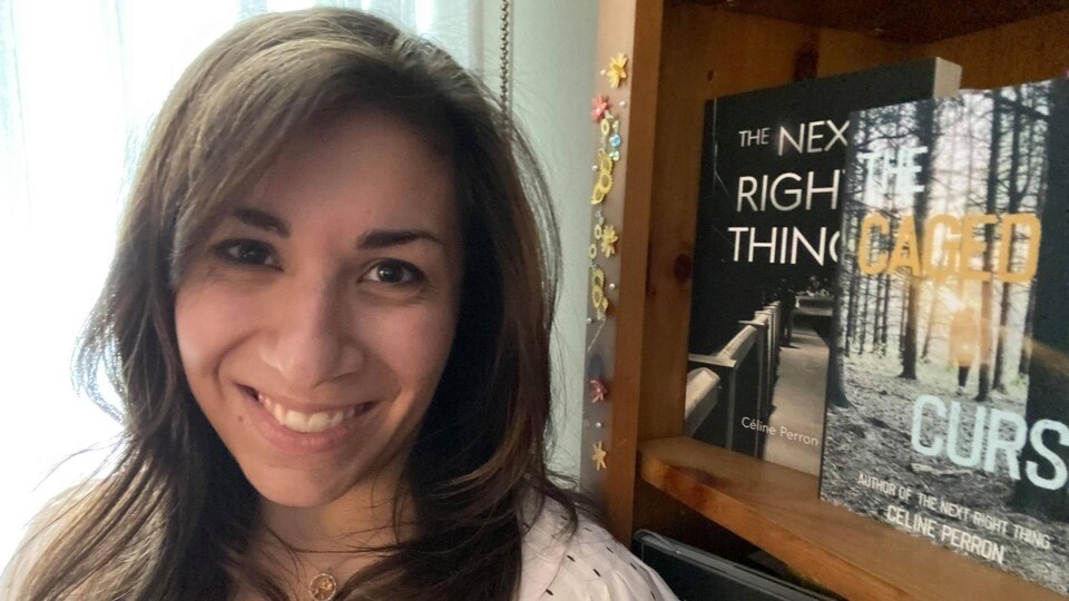 Céline Perron devant sa bibliothèque qui tient ses deux livres.