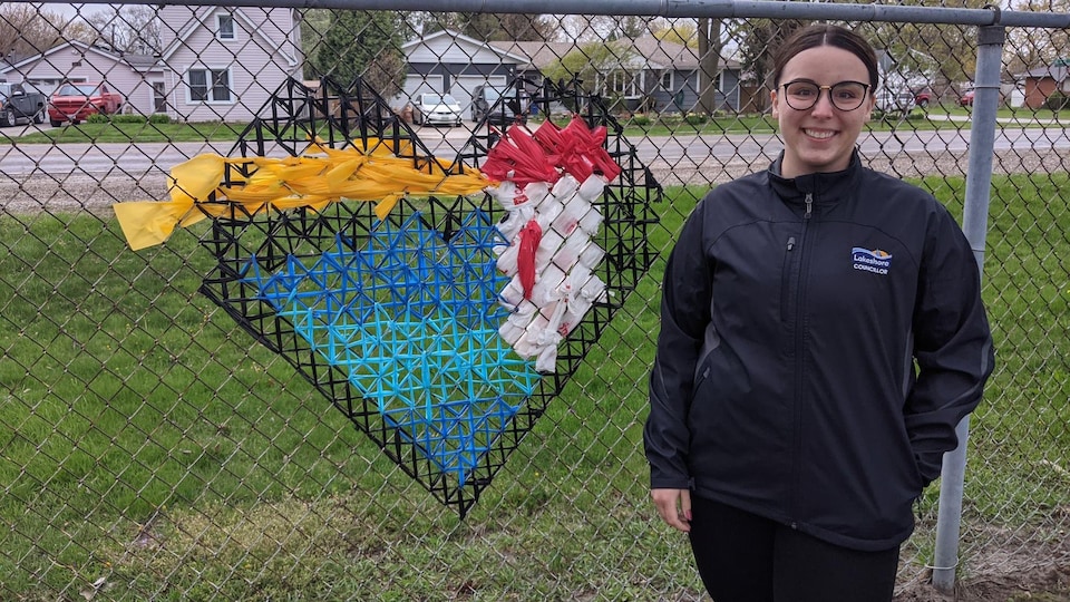 Kelsey Santarossa devant son projet artistique, un coeur situé sur une cloture