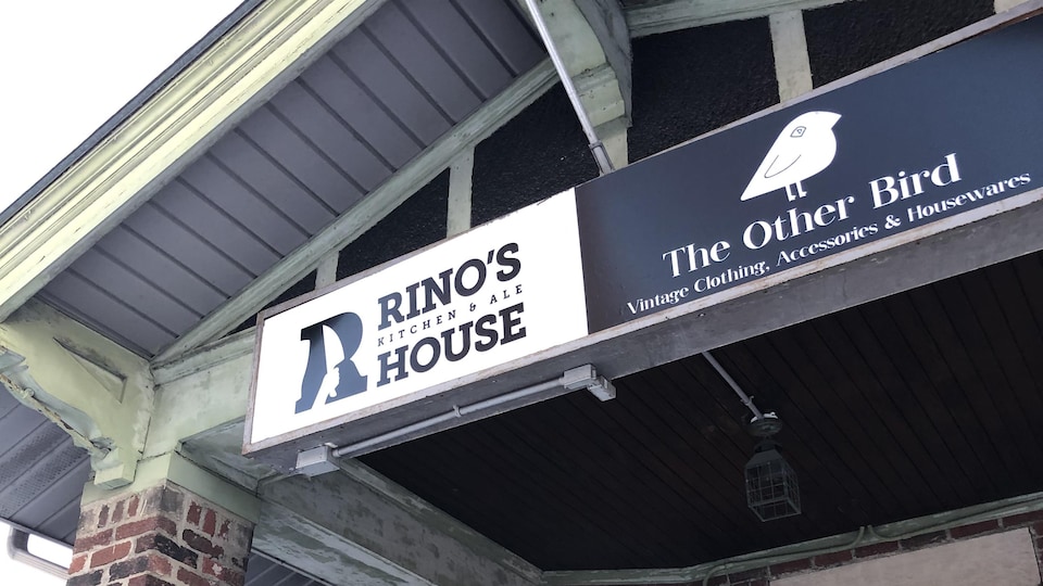 une affiche devant d'une maison qui indique le nom du restaurant Rino's Kitchen.