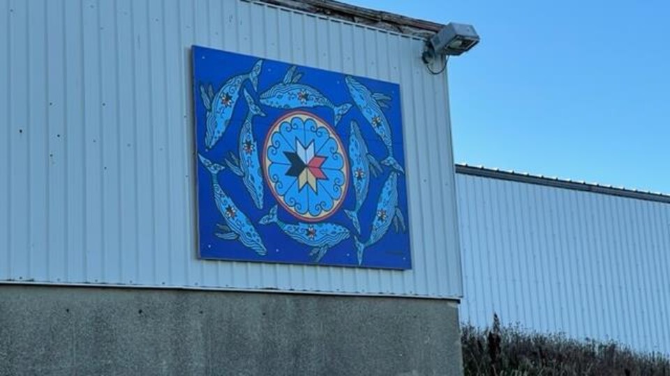 Une murale bleue composée d'images de baleines est installée sur un mur extérieur.