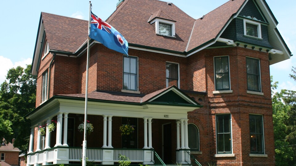 La maison vue de l'extérieur. Un drapeau de l'Aviation royale du Canada flotte devant.