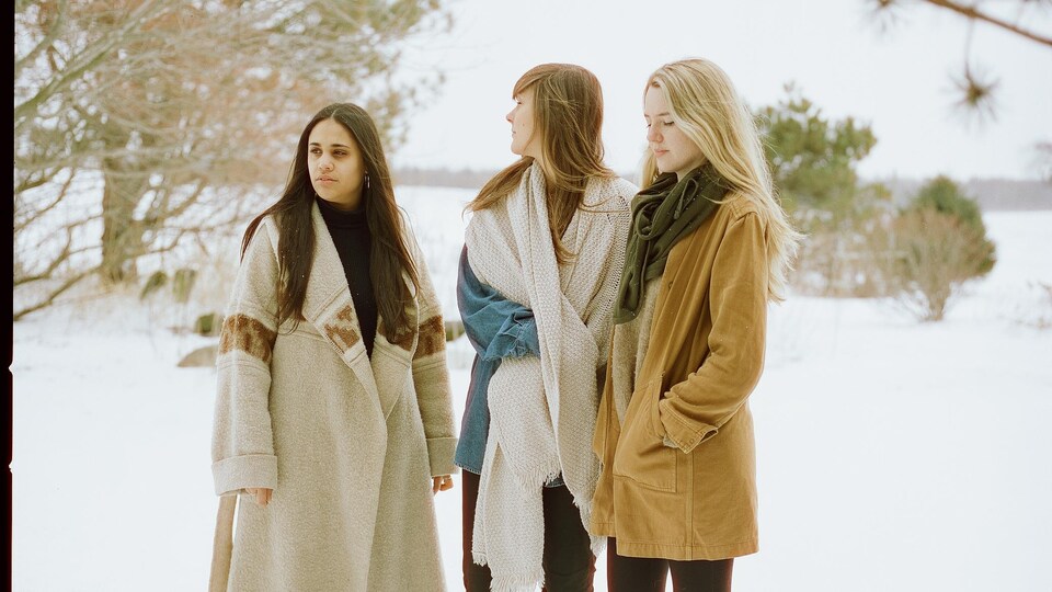 Les trois femmes debouts dans la neige en campagne.