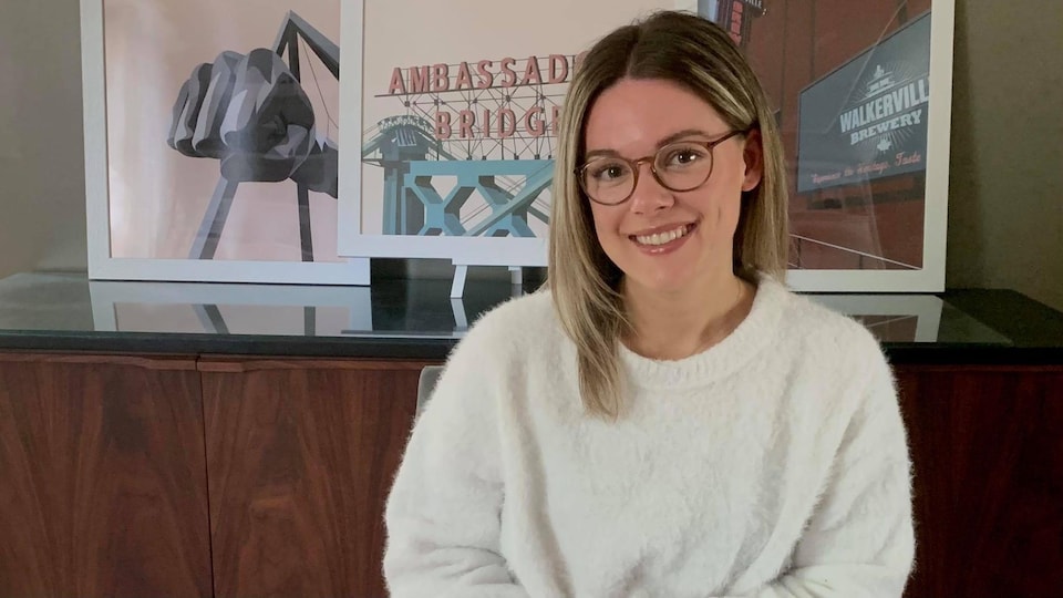Natalie Gagné sourit avec ses oeuvres derrière elle.