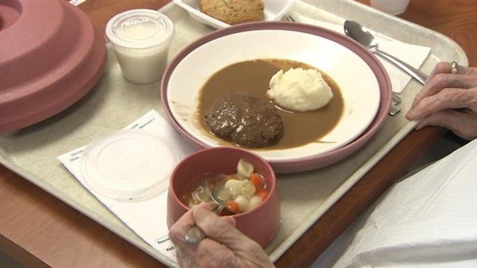 Un repas avec une soupe aux nouilles et une boulette à la viande en CHSLD.
