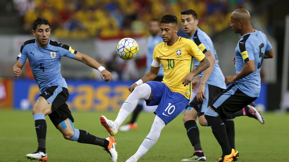 Trois joueurs uruguayens tentent d'enlever le ballon à un joueur brésilien.