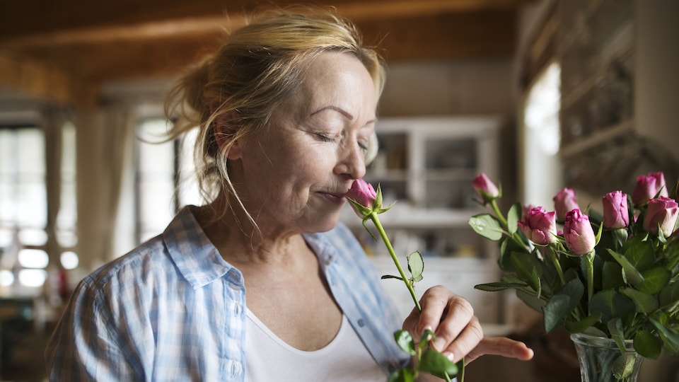 Une femme âgée sent une rose.