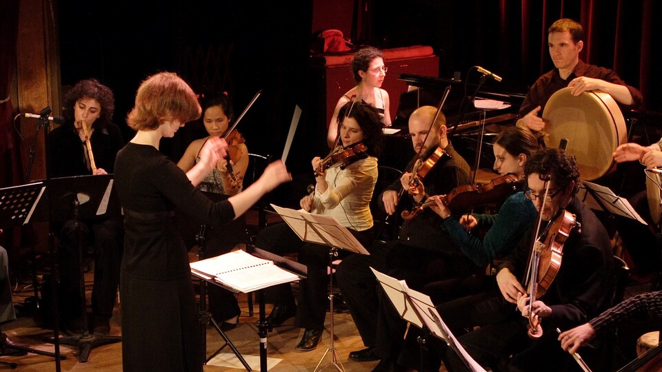 Katia Makdissi-Warren dirige Oktoécho. Elle est face à l'orchestre et dos au public.