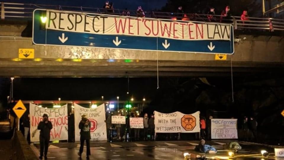 Des hommes et femmes dans la nuit qui protestent avec des banderoles.