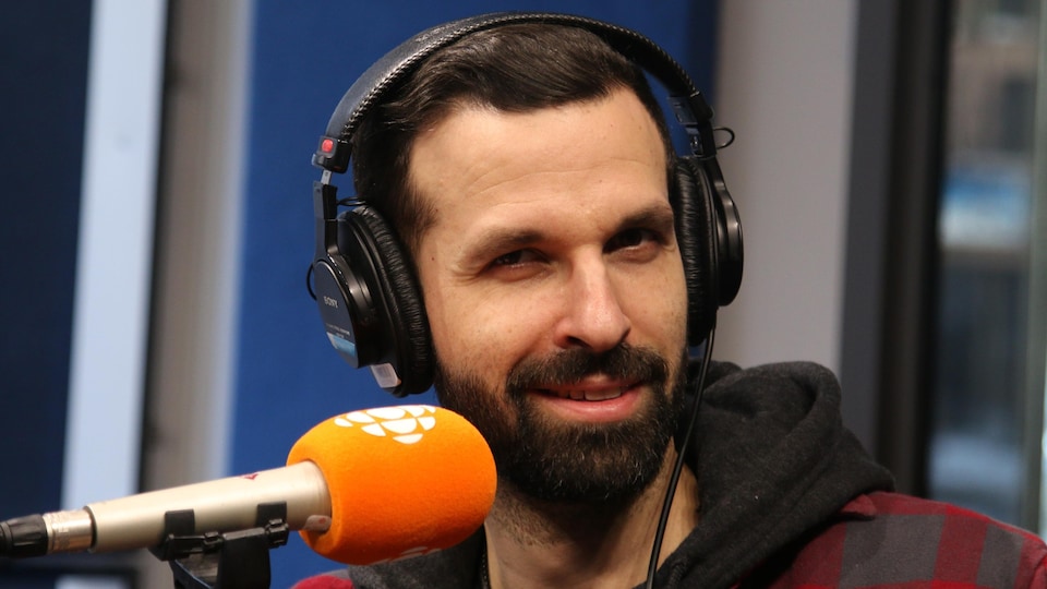 Un homme sourit devant le micro.