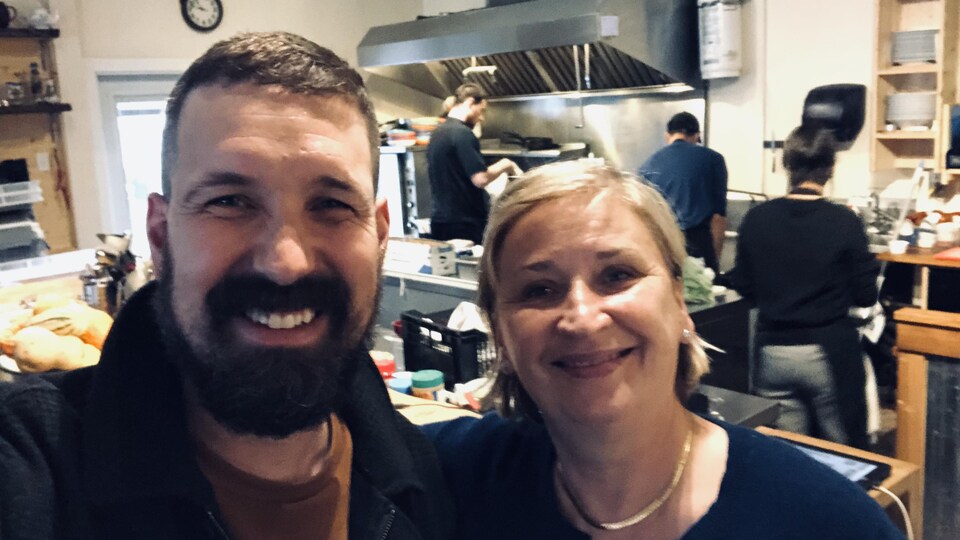 un homme et une femme posent pour un égoportrait dans les cuisines d'un restaurant