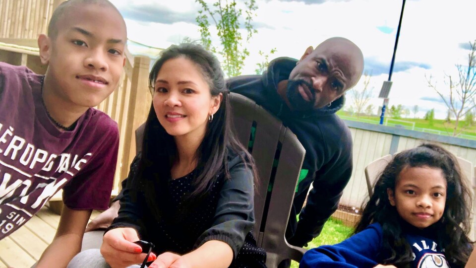 Une famille se tient sur une terrasse en été.