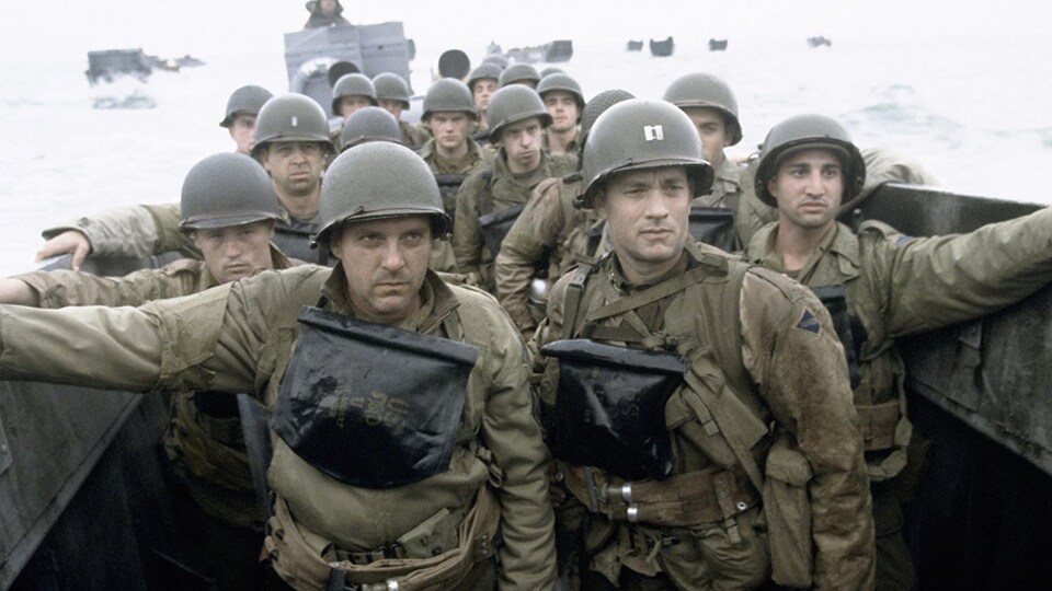Des soldats en uniforme dans un bateau, le regard porté au loin.