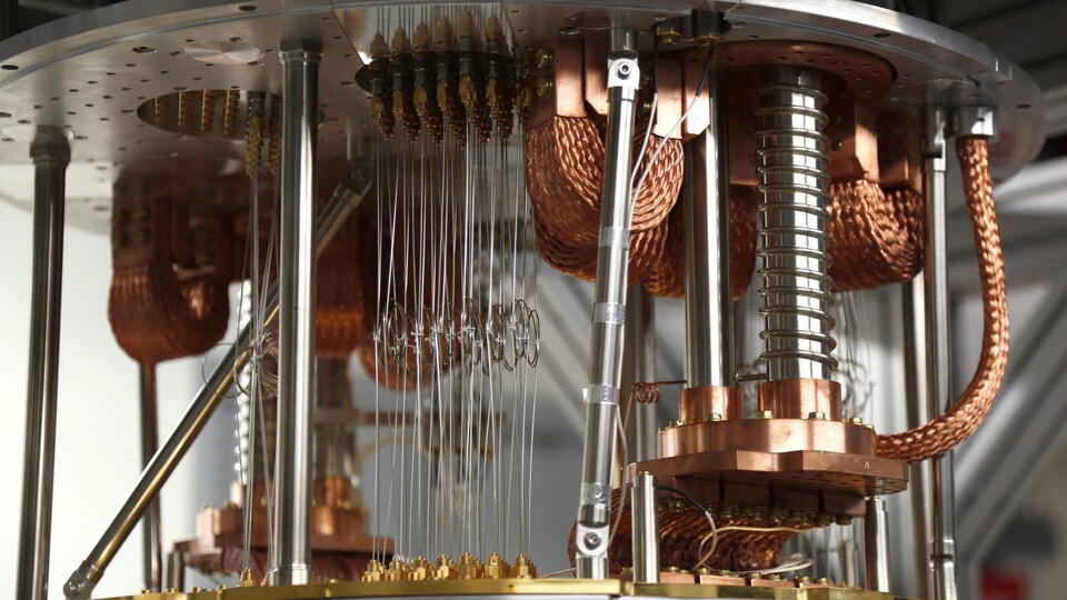 Une photo d'ordinateur quantique, composé de câbles cuivrés et de petits fils d'aluminium tendus entre deux plaques métalliques.