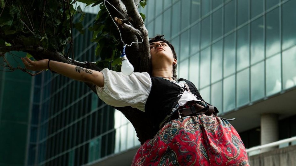 Une artiste en danse s'adosse à un arbre lors d'une chorégraphie. 