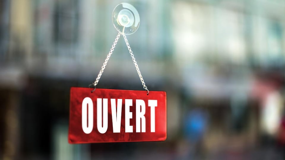 Gros plan sur une pancarte Ouvert d'une fenêtre d'un commerce.