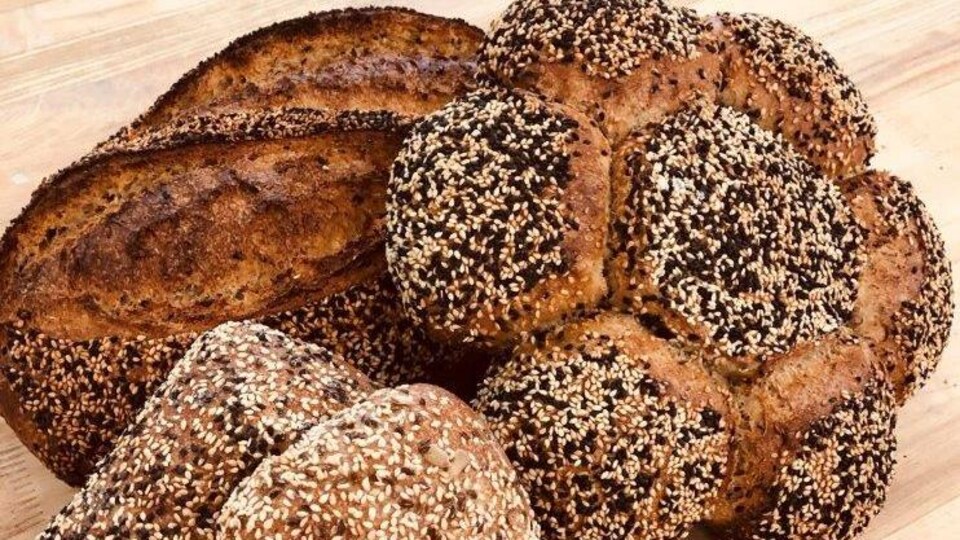 Des pains couverts de grains de différentes formes sur une table