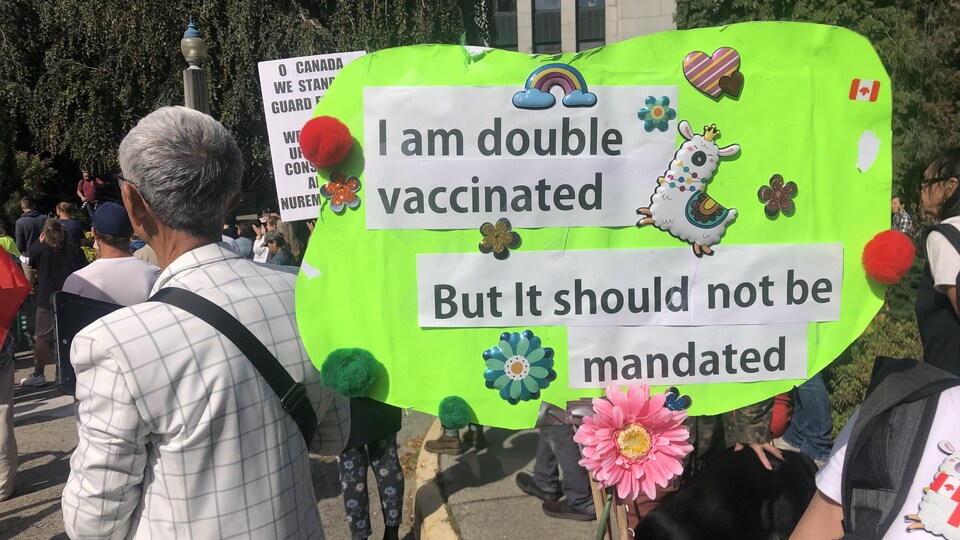 Une manifestante tient une pancarte contre l'entrée en vigueur du passeport vaccinal en Colombie-Britannique