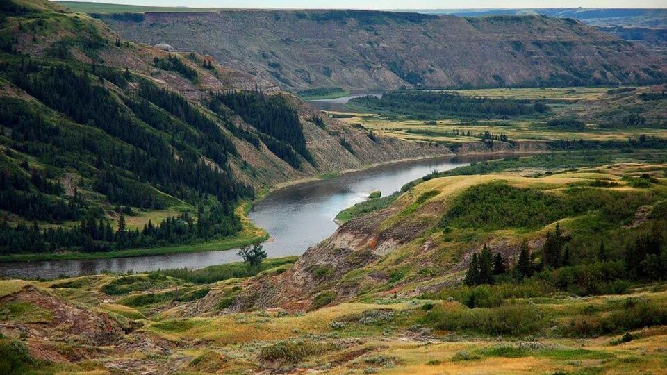 Une rivière coule entre des collines boisées.