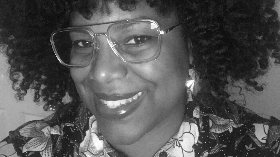 Pascale Mathurin porte de grosses lunettes à la monture transparente sous un afro bien coiffé.