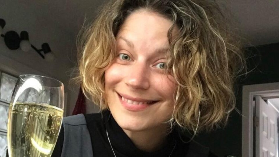 Pascale Turbide, sommelière, souriant et tenant une bouteille et un verre de champagne.