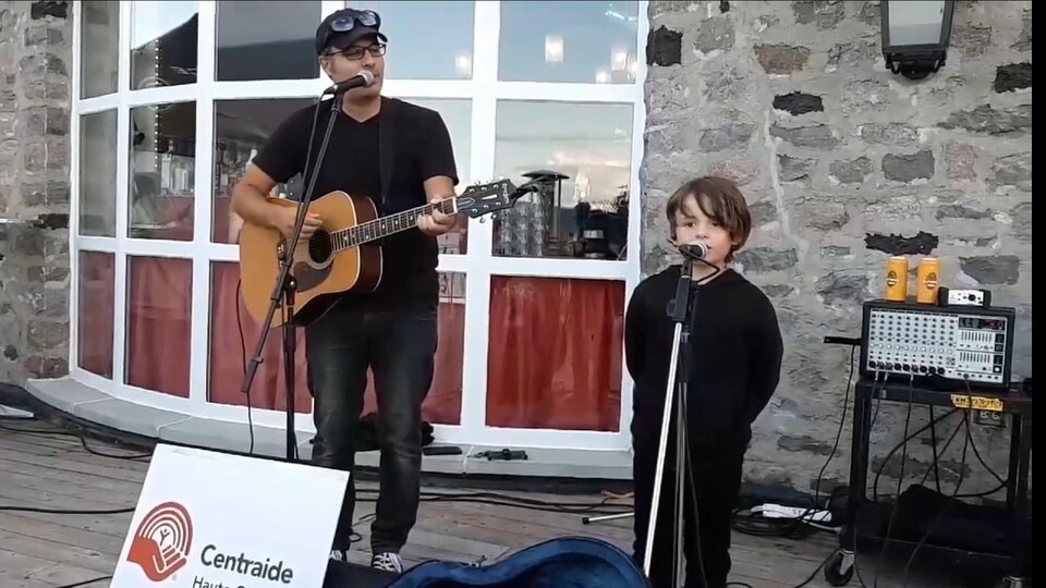 Patrick Desbiens partageant le micro avec son fils pour récolter des dons pour l'organisme Centraide Haute-Côte-Nord.