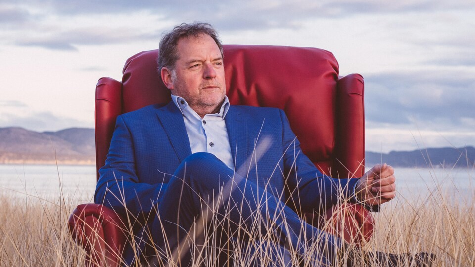 Paul Doucet assis dans un fauteuil dans un champs.