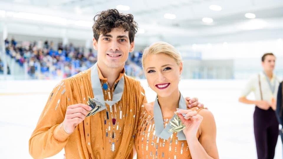 Deux patineurs artistiques posent avec une médaille d'or au cou