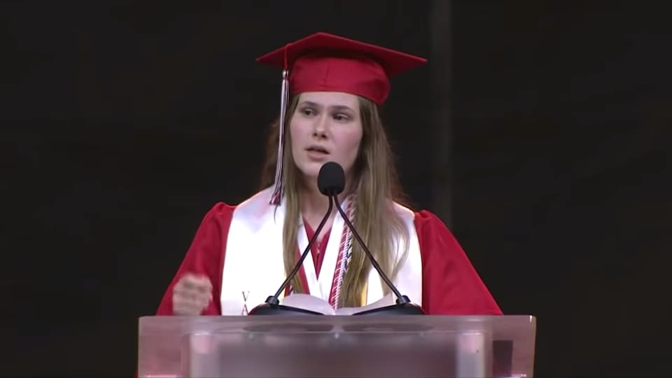 Une jeune femme fait un discours à la cérémonie de remise des diplômes.