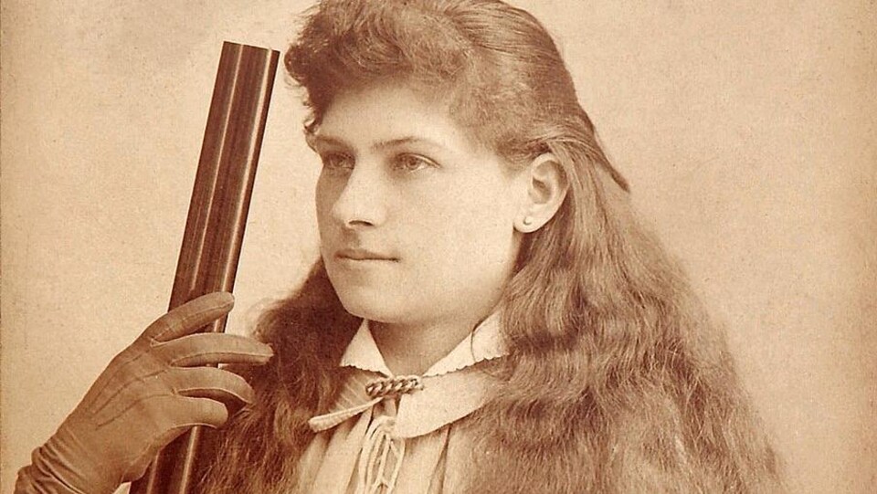 Une femme tient un fusil.