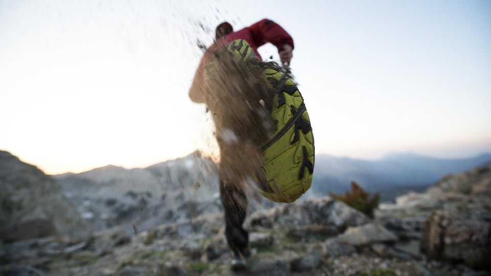 Photo prise de dos d'un homme qui court sur le sommet d'une montagne. 