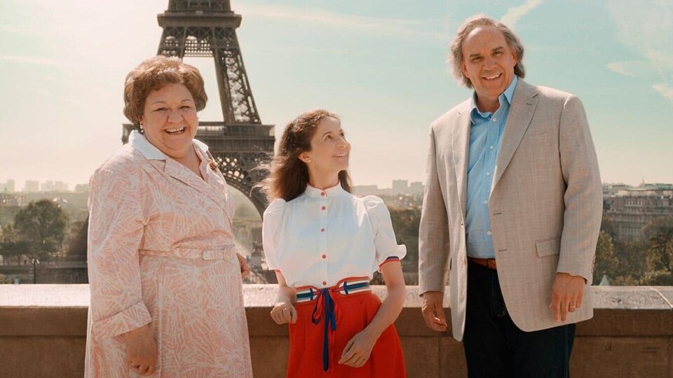 Les trois personnes posent devant la tour Eiffel à Paris.