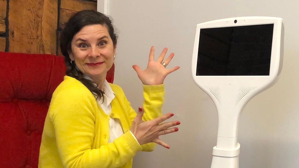 La femme pose à côté d'un robot doté d'un grand écran.
