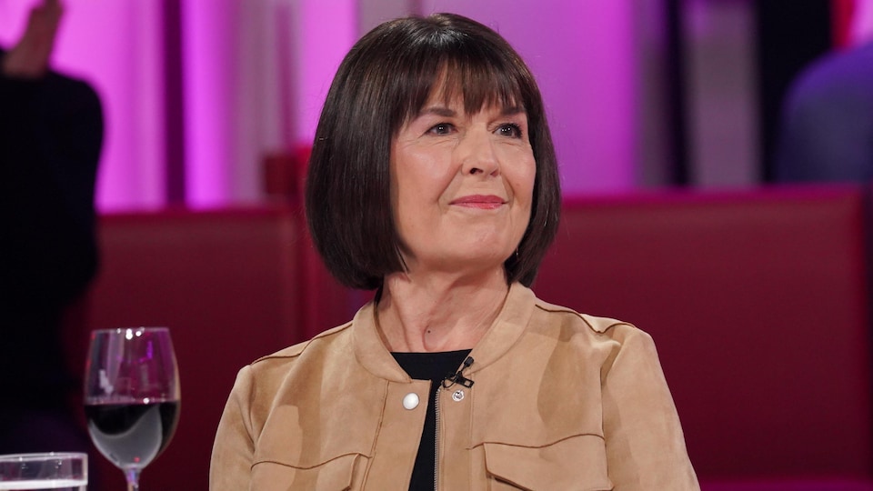 La femme est assise dans un studio de télé.