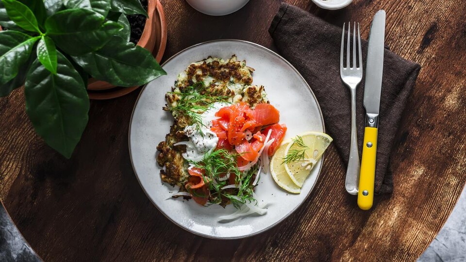 Une assiette garnie de crêpes de légumes, saumon fumé et yaourt grec.