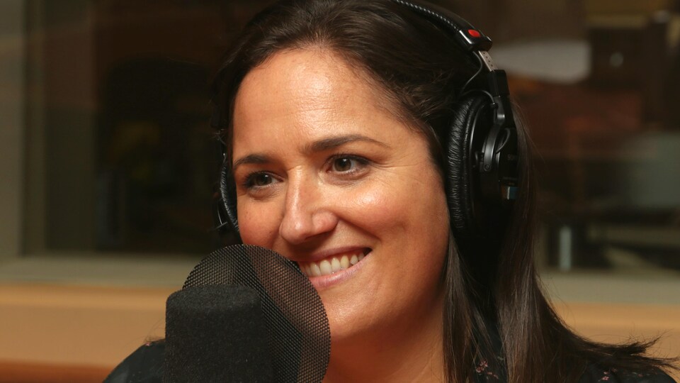 Photo de Caroline Huard devant un micro de radio.