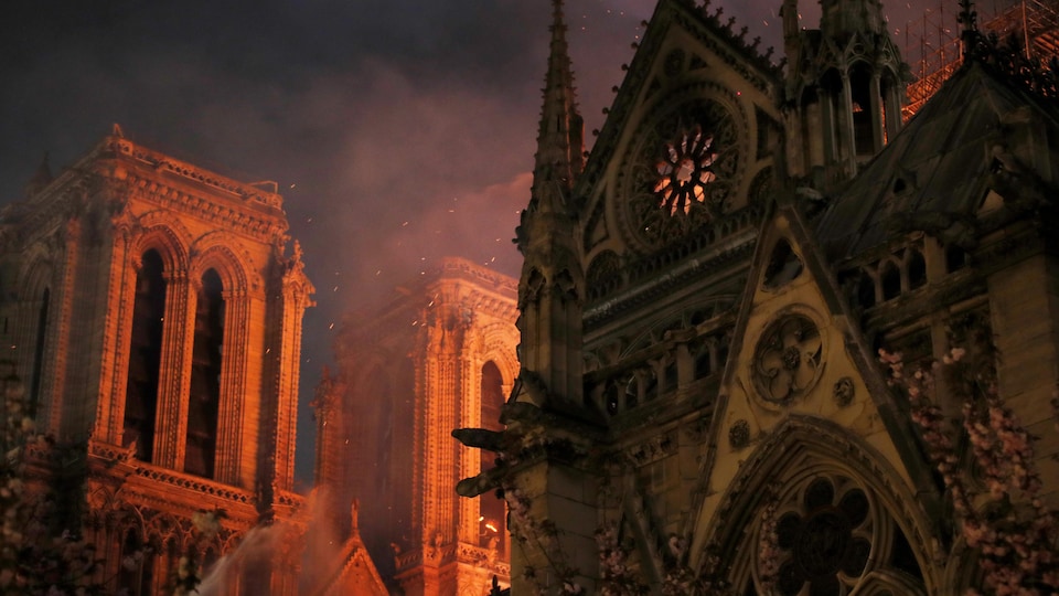 Des étincelles remplissent l'air alors que des pompiers de Paris pulvérisent de l'eau pour éteindre les flammes lors de l'incendie de la cathédrale Notre-Dame de Paris.