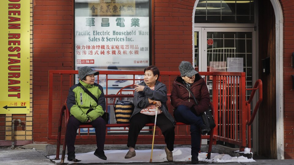 Trois femmes d'origine asiatique discutent, assises sur un banc du quartier chinois de Calgary.