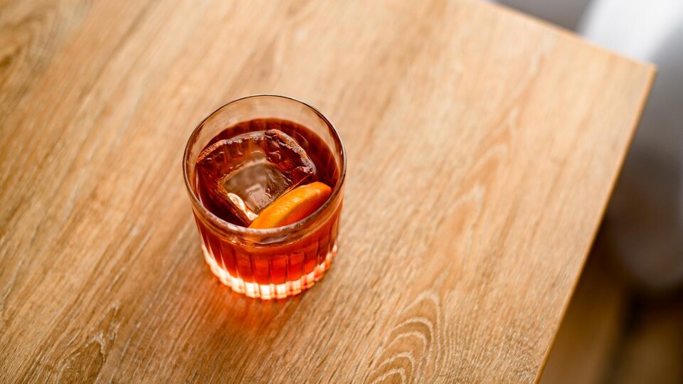 Un cocktail servi dans un verre avec de la glace et une rondelle d'orange.