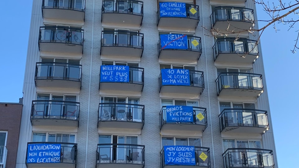 Des pancartes dénonçant des évictions sont accrochées aux balcons d'un immeuble. 