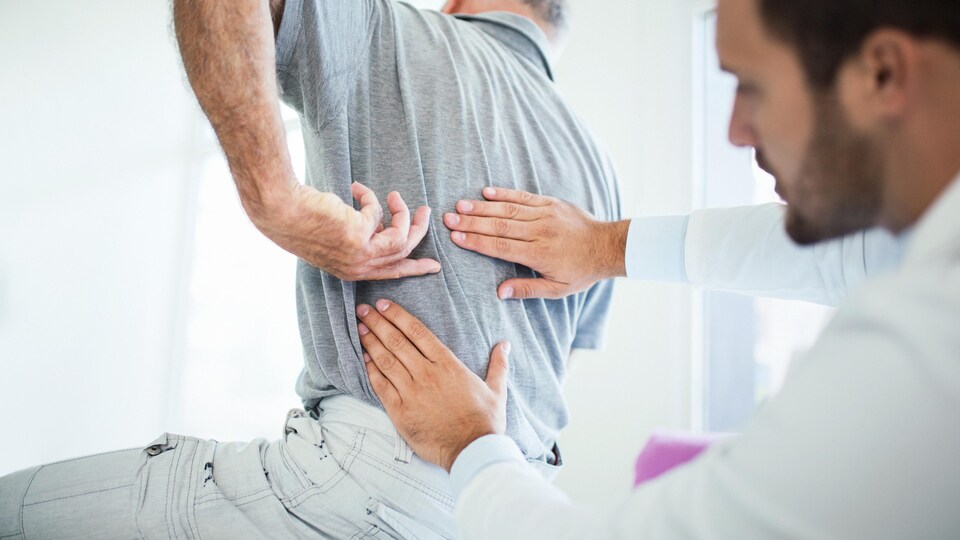 Un monsieur fait traiter ces maux de dos par un médecin.