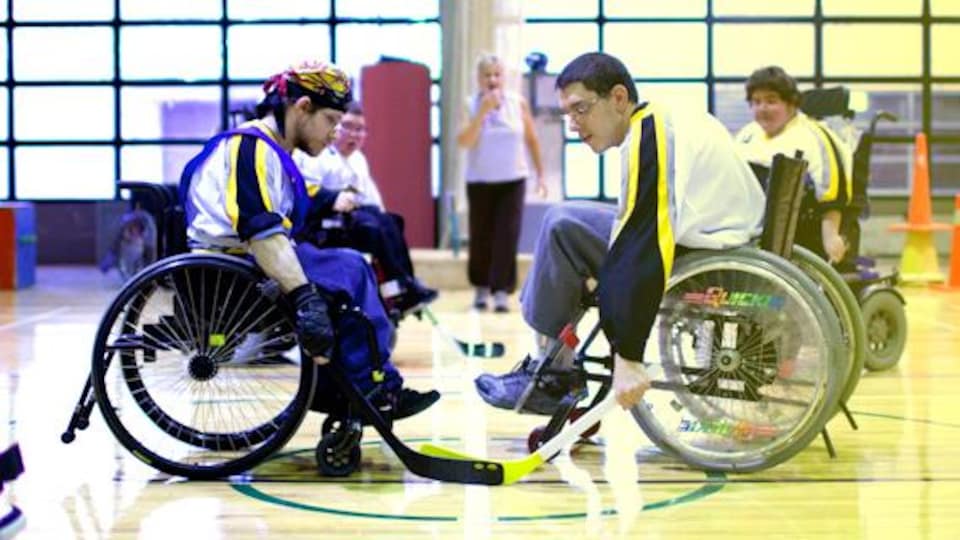 Deux adolescents en fauteuil roulant jouent au hockey.